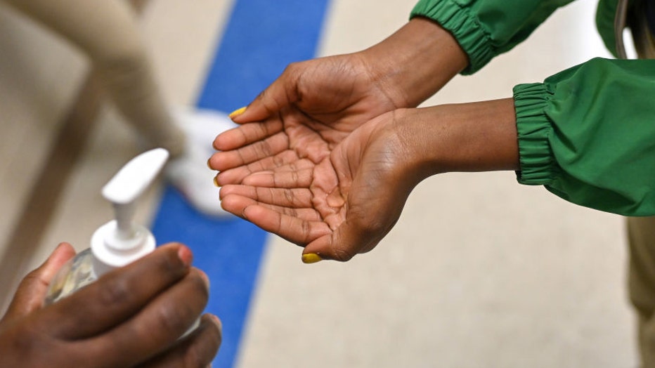 FILE IMAGE - A person puts hand sanitizer in the hands of another in a file image dated Dec. 9, 2022. (Photo by Joshua Lott/The Washington Post via Getty Images)