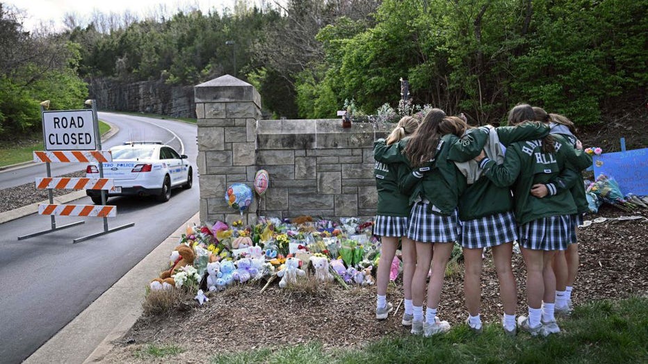 Girls embrace in front of a makeshift memorial for victims by the Covenant School building at the Covenant Presbyterian Church following a shooting, in Nashville, Tennessee, on March 28, 2023. (Photo by BRENDAN SMIALOWSKI/AFP via Getty Images)