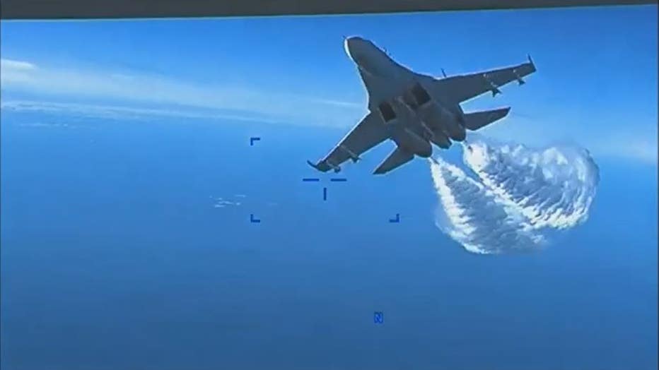 A screengrab taken from video released on March 16, 2023, shows a Russian Su-27 approaching the back of the MQ-9 drone and beginning to release fuel as it passes over the Black Sea, according to the Pentagon. (Credit: U.S. Department of Defense)