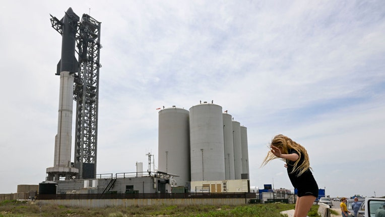 A girl leaps off a concrete barrier while checking out SpaceXs Starship spacecraft and Super Heavy rocket on the launch pad at Starbase on April 16, 2023. (Photo by Jonathan Newton/The Washington Post via Getty Images)