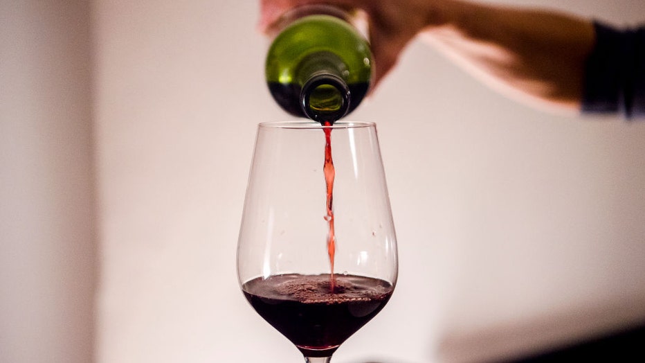 FILE - A woman pours wine into a glass at home. (Photo by Finn Winkler/picture alliance via Getty Images)