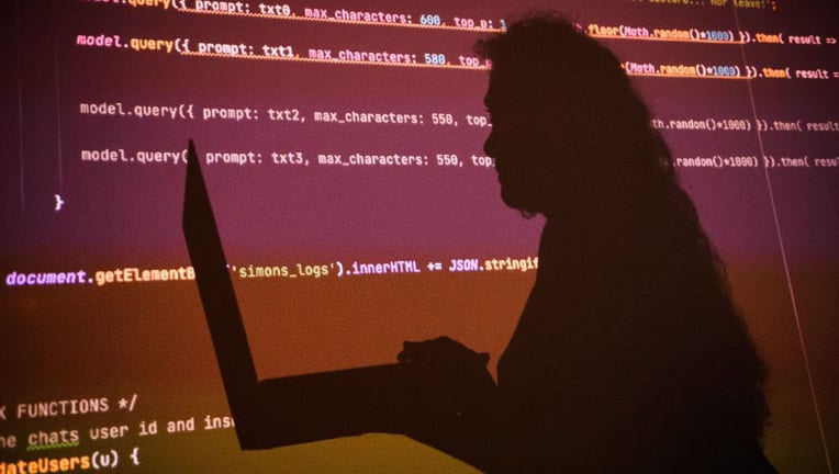 FILE - The shadow of a developer poses in front of a text generated by artificial intelligence on July 14, 2022. (Photo by CLEMENT MAHOUDEAU/AFP via Getty Images)