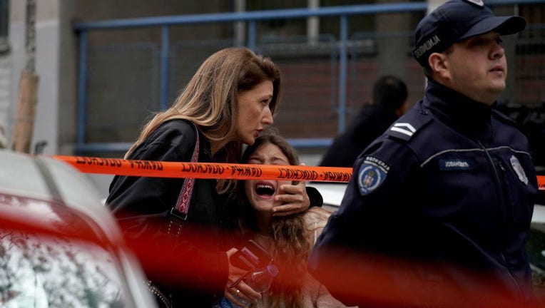 A parent escorts her child following a shooting at a school in the capital Belgrade on May 3, 2023. (Photo by OLIVER BUNIC/AFP via Getty Images)