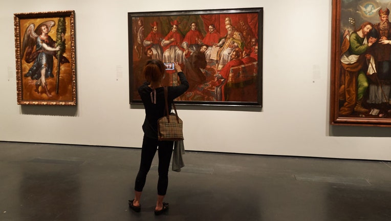 FILE - A visitor takes a picture of Luis Berrueco, "Saint Francis before Pope Honorius III, (c, 1710) on display at the Press Preview For LACMAs "Archive Of The World" Exhibition at Los Angeles County Museum of Art on June 8, 2022, in Los Angeles, California. (Photo by Unique Nicole/Getty Images)