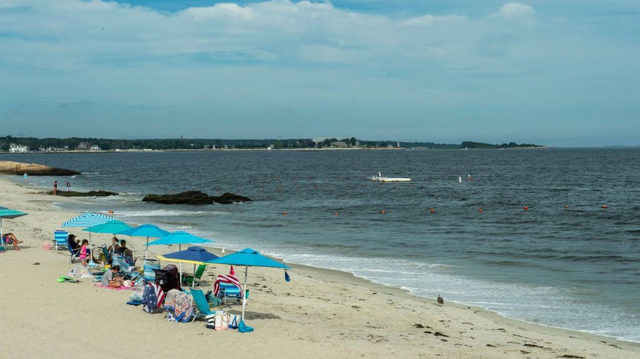 FILE - People sit in the sun on Guthrie Beach before the arrival of Hurricane Henri in New London, Connecticut on August 21, 2021. (Photo by JOSEPH PREZIOSO/AFP via Getty Images)