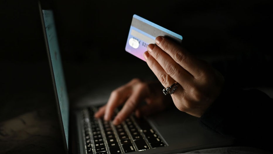 FILE - An illustrative image of a person holding a credit card while shopping online on a computer. (Photo by Artur Widak/NurPhoto via Getty Images)