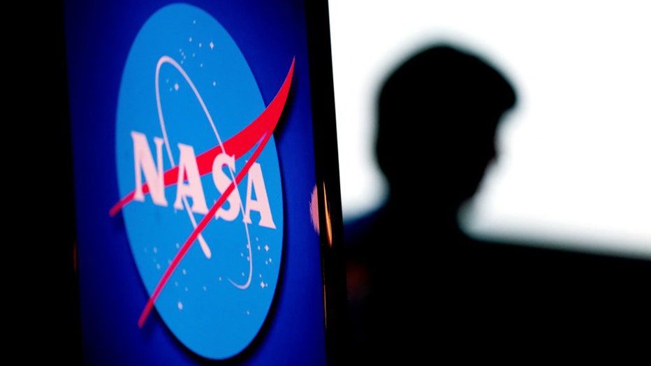 FILE - The silhouette of a NASA employee is seen past the NASA logo in the Webb Auditorium at NASA headquarters in Washington, DC, on June 7, 2022. (Photo by STEFANI REYNOLDS/AFP via Getty Images)