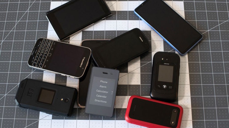 FILE - A Light Phone 2 (center) is surrounded by smartphones in a file image dated March 24, 2023. (Photo by JASON CONNOLLY/AFP via Getty Images)