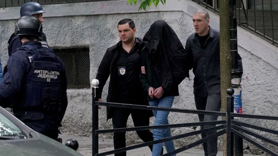 Police officers escort a minor who is suspected of firing several shots at a school in the capital Belgrade on May 3, 2023. (Photo by OLIVER BUNIC/AFP via Getty Images)