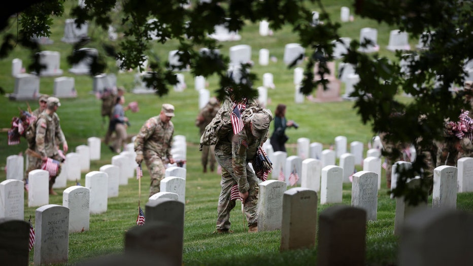 Members of the 3rd U.S. Infantry Regiment place flags at the headstones of U.S. military personnel buried at Arlington National Cemetery, in preparation for Memorial Day, on May 25, 2023 in Arlington, Virginia. (Photo by Win McNamee/Getty Images)