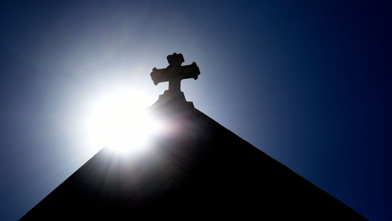 FILE - The sun rises behind a stone cross atop a Catholic church in Santa Fe, New Mexico. (Photo by Robert Alexander/Getty Images)