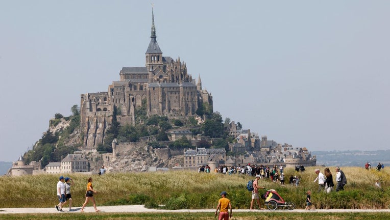 People walk past Frances Mont-Saint-Michel during the French Presidents two-day visit in Normandy, in Le Mont-Saint-Michel, north-western France, on June 5, 2023. (Photo by LUDOVIC MARIN/POOL/AFP via Getty Images)