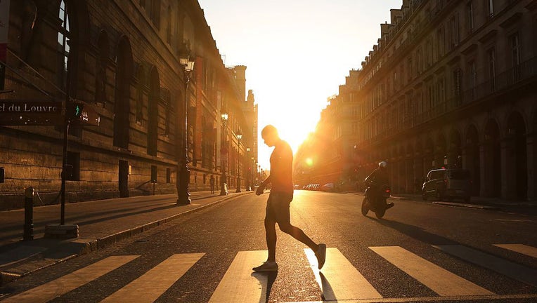 FILE - A man walks across the street at sunset in Paris on June 8, 2015. (Photo credit: LUDOVIC MARIN/AFP via Getty Images)