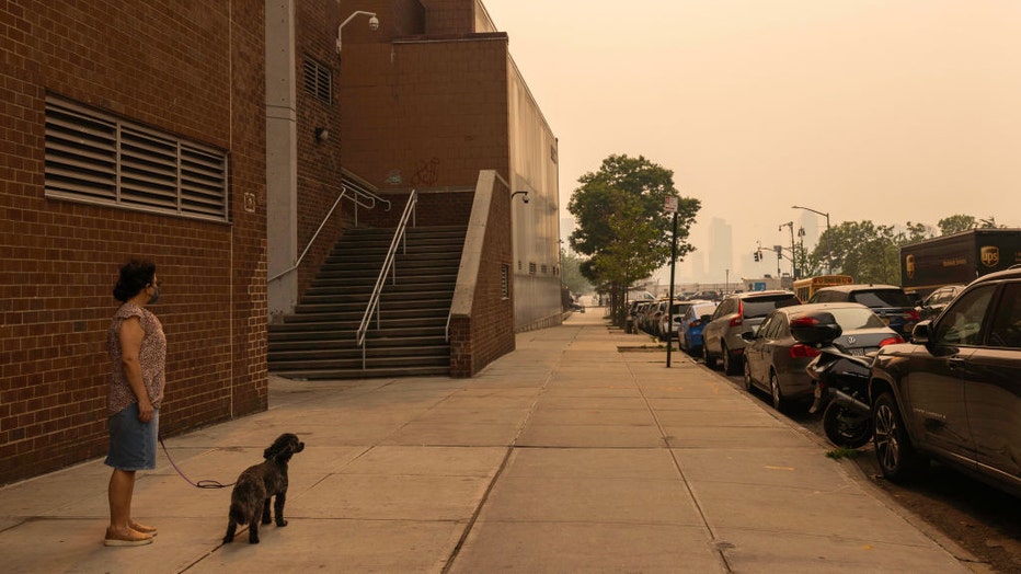 A pedestrian walks her dog as smoke from Canada wildfires blankets New York, US, on June 7, 2023. Photographer: Alex Kent/Bloomberg via Getty Images