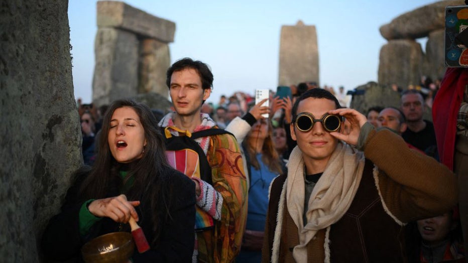 FILE - Revellers celebrate the Summer Solstice as the sun rises at Stonehenge, near Amesbury, in Wiltshire, southern England on June 21, 2023, in a festival, which dates back thousands of years, celebrating the longest day of the year when the sun is at its maximum elevation. (Photo by DANIEL LEAL/AFP via Getty Images)