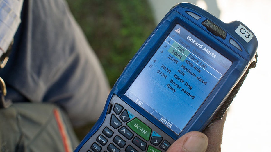FILE - United States Postal Service (USPS) mailman Mike Micali displays a hand held scanning device that shows the "Trip Hazards" feature, which alerts to nearby dogs, during deliveries in Flemington, New Jersey, U.S., on Aug. 4, 2016. Photographer: Ron Antonelli/Bloomberg via Getty Images