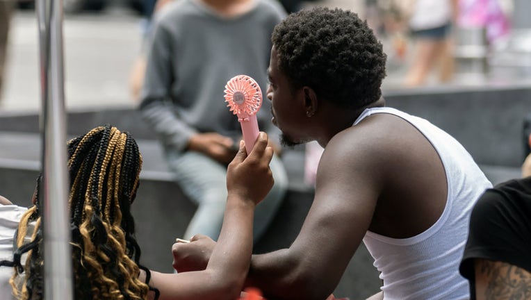 FILE - Visitors use a handheld fan during a heat wave in New York, on July 27, 2023. Photographer: Jeenah Moon/Bloomberg via Getty Images