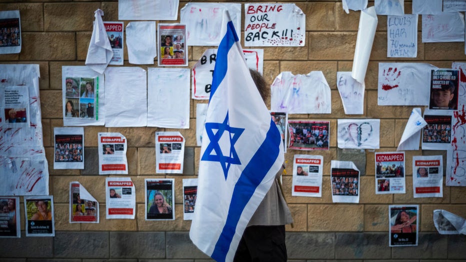 An Israeli woman holding a flag reacts to posters of kidnapped Israelis by Hamas on Oct. 15, 2023, in Tel Aviv, Israel. (Photo by Ilia Yefimovich/picture alliance via Getty Images)
