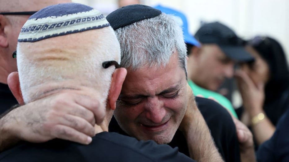 The father of Naor Hassisim is comforted during his sons funeral, a victim of the Kibbutz Kfar Aza attack last week by members of the Palestinian militant group Hamas, at a cemetery, in southern Israeli city of Ashdod on Oct. 16, 2023. (Photo by GIL COHEN-MAGEN/AFP via Getty Images)