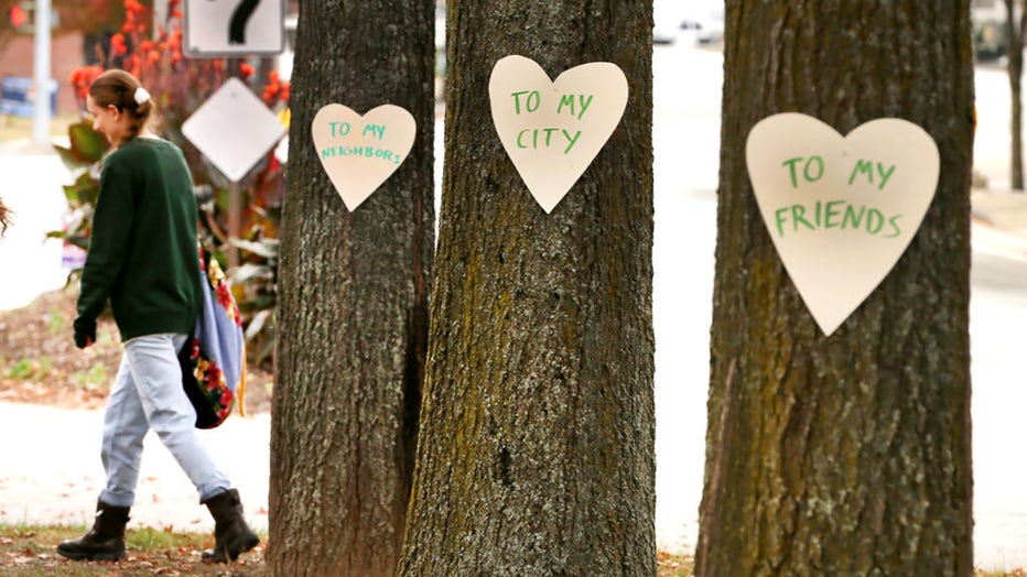 Lewiston, ME - October 26: Artist Miia Zellner walks away after nailing hearts she made to trees on Main Street the day after a mass shooting took place in the city. (Photo by John Tlumacki/The Boston Globe via Getty Images)