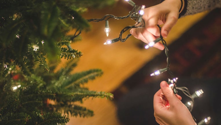 FILE - A person decorates a Christmas tree with lights. (Photo by: GHI/Education Images/Universal Images Group via Getty Images)