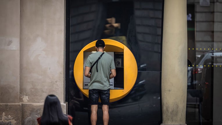 FILE - A customer uses an automated teller machine (ATM) outside a Caixabank SA branch in Barcelona, Spain, on July 26, 2023. Photographer: Angel Garcia/Bloomberg via Getty Images