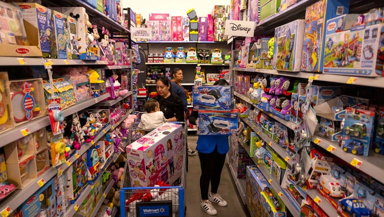 FILE - An employee stocks toy department shelves as shoppers peruse merchandise at the Walmart Supercenter on Nov. 14, 2023, in Burbank, CA. (Brian van der Brug / Los Angeles Times via Getty Images)