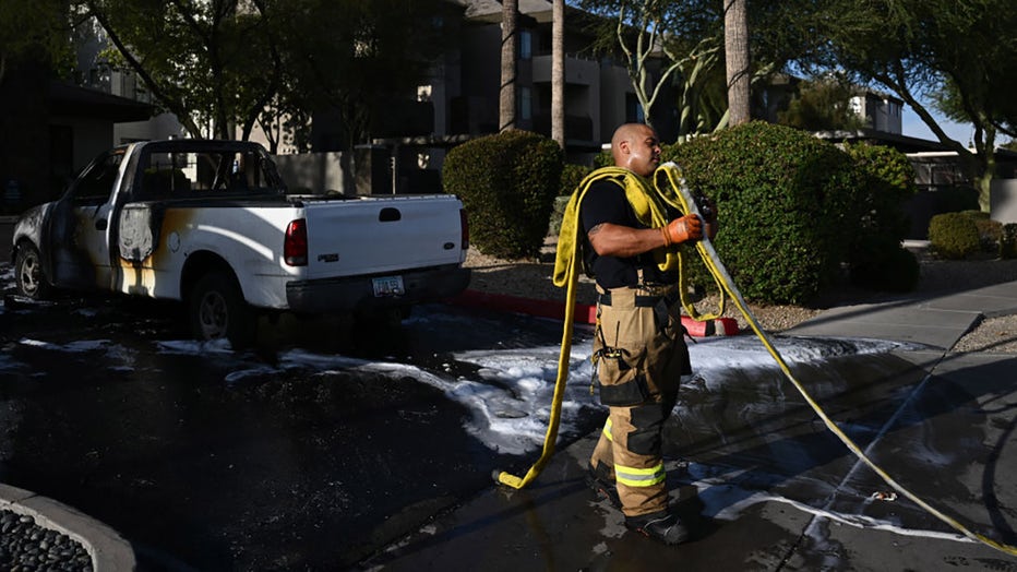 FILE - A Phoenix Fire Department firefighter sweats while gathering a hose line after extinguishing a Ford F150 pickup truck fire during a record heat wave in Phoenix, Arizona on July 18, 2023. (Photo by PATRICK T. FALLON/AFP via Getty Images)
