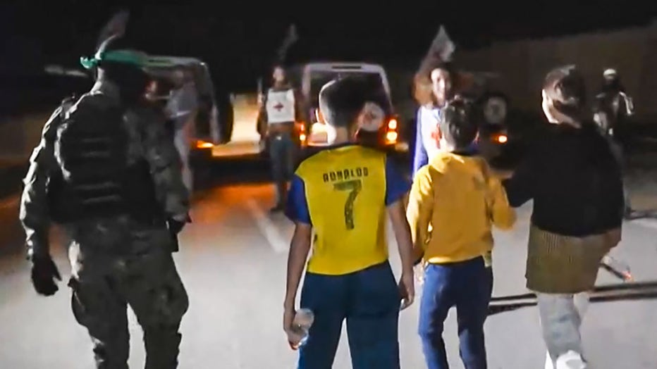 An image grab from a handout video released by the Hamas Media Office shows newly released Israeli hostage 12-year-old Eitan Yahalomi (C) escorted to a Red Cross vehicle in the Gaza Strip on Nov. 27, 2023. (Photo by -/HAMAS MEDIA OFFICE/AFP via Getty Images)