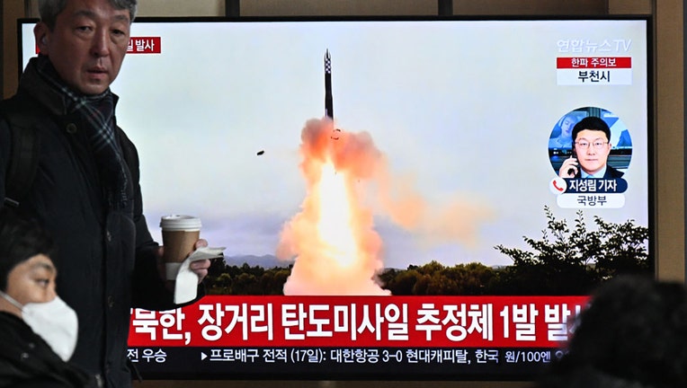 A man walks past a television screen showing a news broadcast with file footage of a North Korean missile test, at a railway station in Seoul on Dec. 18, 2023. (Photo by ANTHONY WALLACE/AFP via Getty Images)