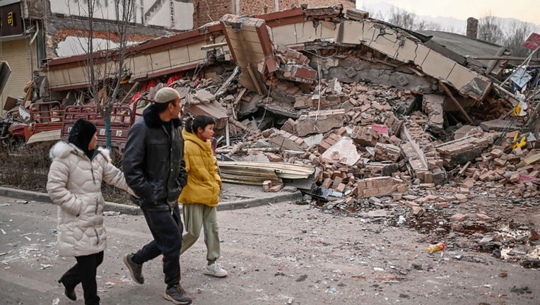 People walk past a collapsed building after an earthquake in Dahejia, Jishishan County in northwest Chinas Gansu province on Dec. 19, 2023. (Photo by PEDRO PARDO/AFP via Getty Images)