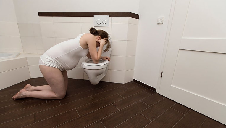 FILE - A pregnant woman feeling sick over a toilet. (Photo by Classen/ullstein bild via Getty Images)