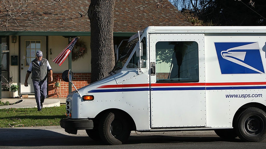 FILE - A US Postal Service letter carrier walks back to his truck after delivering a package in San Lorenzo, California. (Photo by Justin Sullivan/Getty Images)