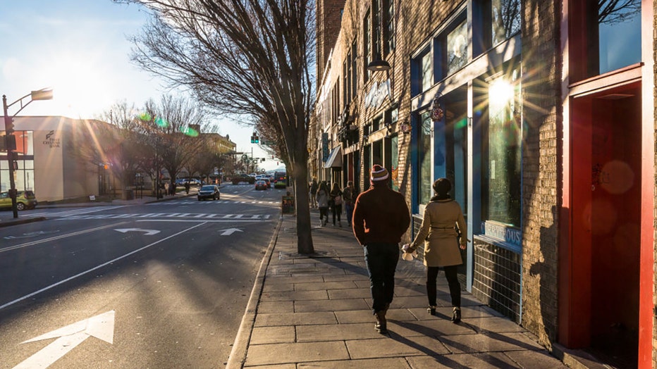 FILE - A couple walk along a sun-drenched Asheville street, NC. (Photo by Christopher Pillitz/Getty Images)