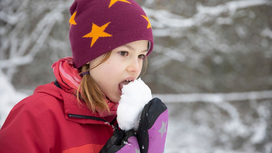 FILE - In this photo illustration, a girl is seen tasting fresh snow on Jan. 9, 2021, in Bonn, Germany. (Photo by Ute Grabowsky/Photothek via Getty Images)