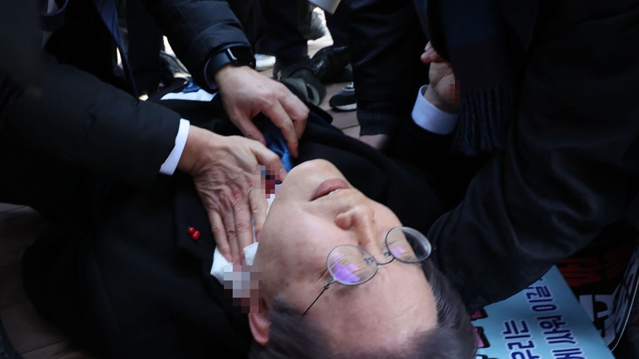 In this handout image provided by The Busan Daily News, Lee Jae-myung, leader of the main opposition Democratic Party, lies down after he was attacked by an assailant of his neck during a visit to the construction site of an airport on Jan. 2, 2024, in Busan, South Korea. (Photo by The Busan Daily News via Getty Images)