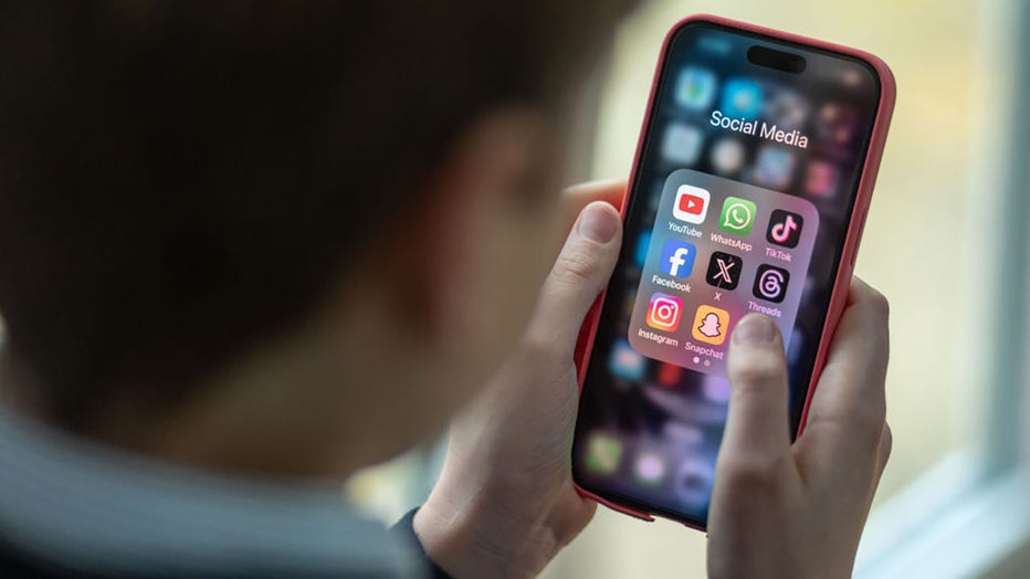 FILE - In this photo illustration, a person looks at an iPhone screen showing various social media apps including TikTok, Facebook and X. (Photo by Matt Cardy/Getty Images)