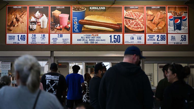 FILE - Customers wait in line to order below signage for the Costco Kirkland Signature $1.50 hot dog and soda combo on June 14, 2022, in Hawthorne, California. (Photo by PATRICK T. FALLON/AFP via Getty Images)