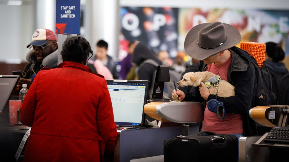 FILE - A traveler holding a dog checks in for a flight at Hartsfield-Jackson Atlanta International Airport (ATL) in Atlanta, Georgia, on Friday, Dec. 22, 2023. Photographer: Dustin Chambers/Bloomberg via Getty Images