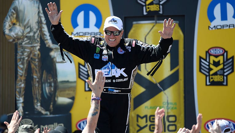 FILE - NHRA Funny Car driver John Force waves to the crowd during driver introductions prior to day three of the NHRA Mile High Nationals at Bandimere Speedway on July 24, 2016. (Photo by Michael Reaves/The Denver Post via Getty Images)