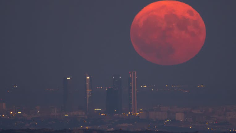 The full Sturgeon Supermoon of August rises over the Madrid skyline, highlighting the skyscrapers of the Four Towers Business Area.