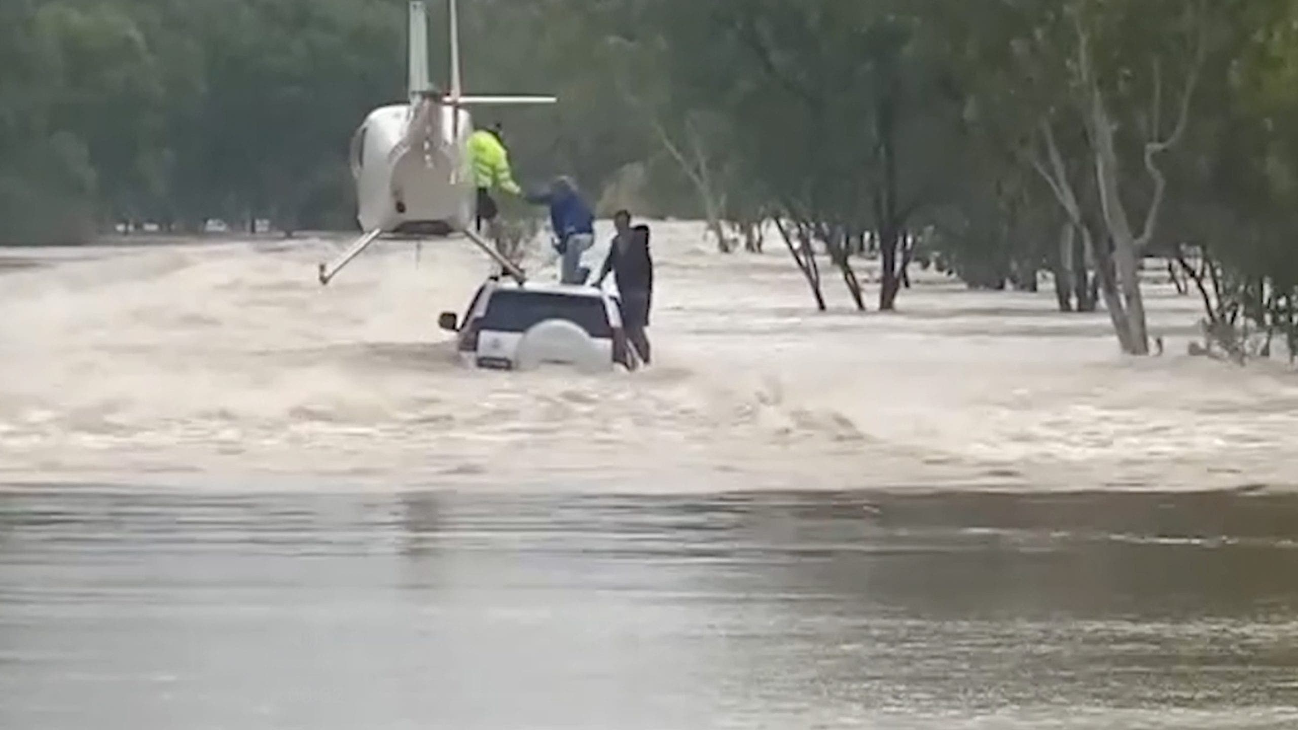 Watch: Pilot lands helicopter on flooded vehicle, saving men and dog