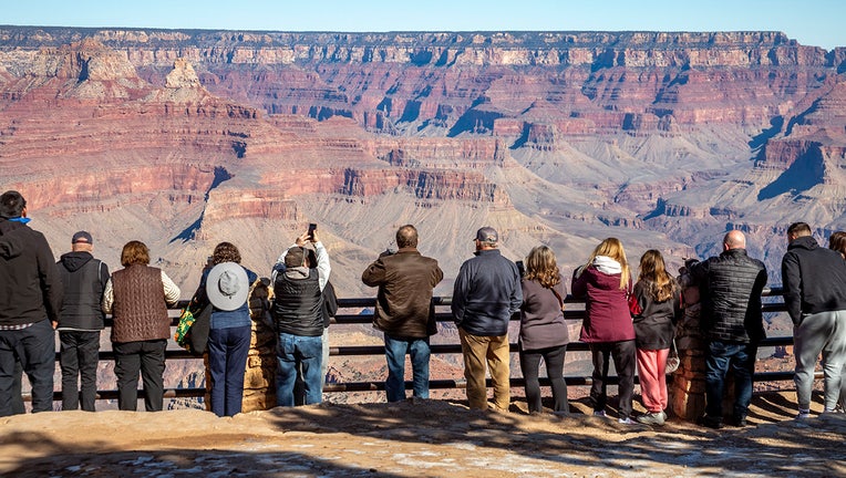 Row of people at rim of Grand Canyon