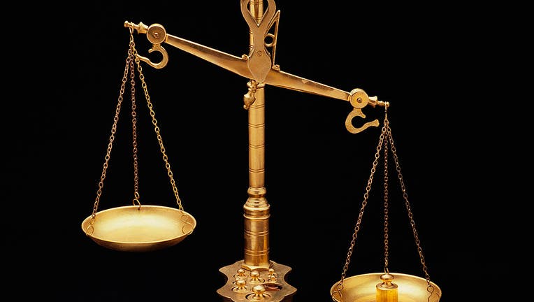 These are the golden Scales of Justice. They represent the legal system and courts. The scales here are shown unbalanced with the left side weighing heavier than the right. They are shown against a black background.