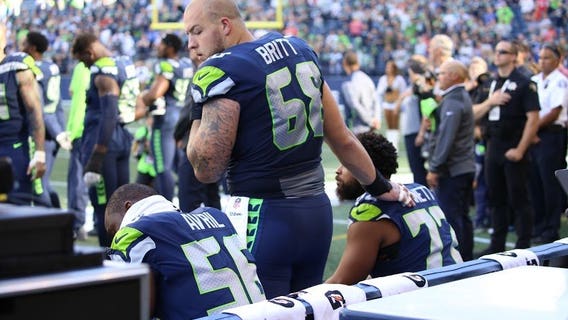 Bennett and Avril sit and Britt stands by in solidarity during national anthem