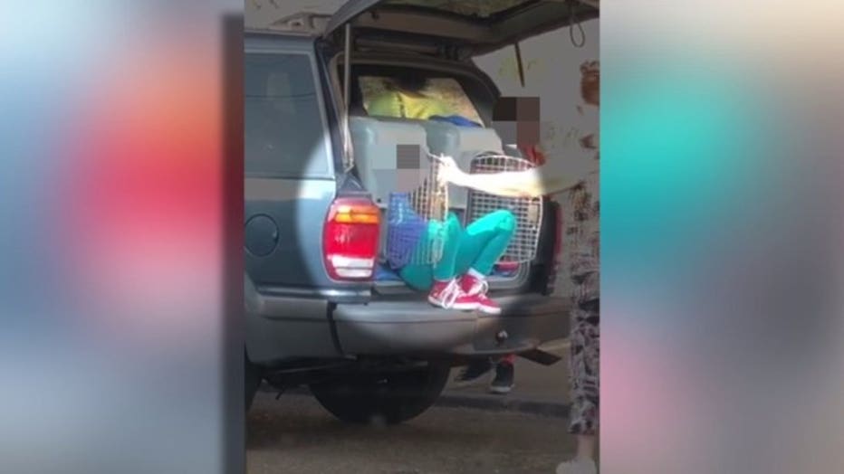 A woman has been arrested after a video shared online showed two children getting out of pet kennels inside the trunk of an SUV.