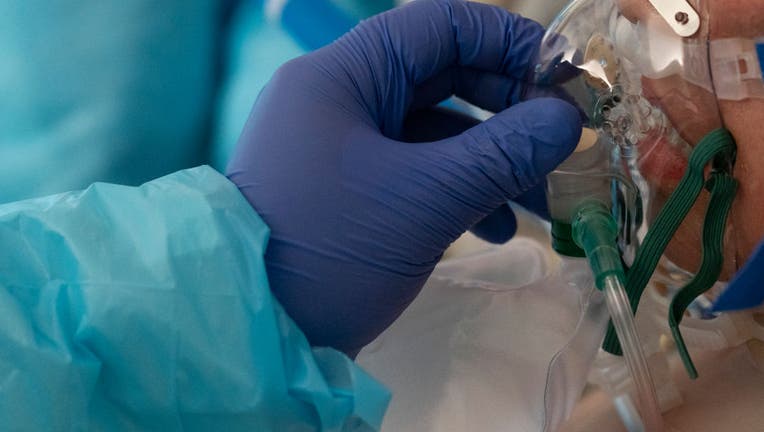 A medical staff member holds an oxygen mask for a patient in the COVID-19 intensive care unit (ICU) at the United Memorial Medical Center on Dec. 21, 2020 in Houston, Texas. (Photo by Go Nakamura/Getty Images)