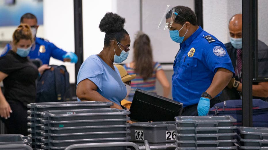 FILE - A TSA worker wears a mask while helping travelers get through a security checkpoint at the Miami International Airport on Nov. 22, 2020 in Miami, Florida. (David Santiago/Miami Herald/Tribune News Service via Getty Images)