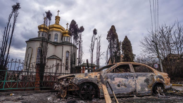 A burnt out car and a damaged church caused by the Russian