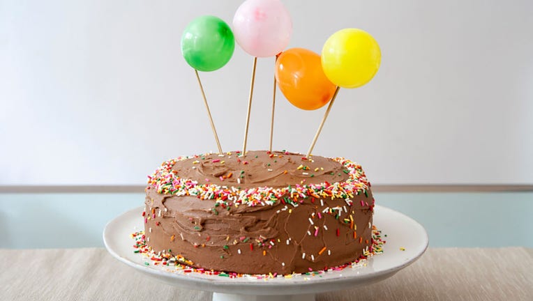 FILE - Birthday cake with chocolate icing decorated with balloons and sprinkles. (Photo by: Education Images/Universal Images Group via Getty Images)
